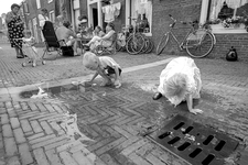 830213 Afbeelding van twee spelende kinderen bij een plas water in de De Kockstraat (Zeven Steegjes) te Utrecht.